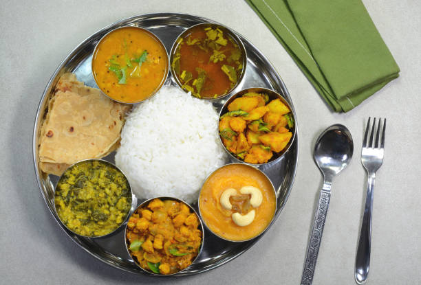 Indian Thali with vegetable dishes, curry, dessert served with rice and roti